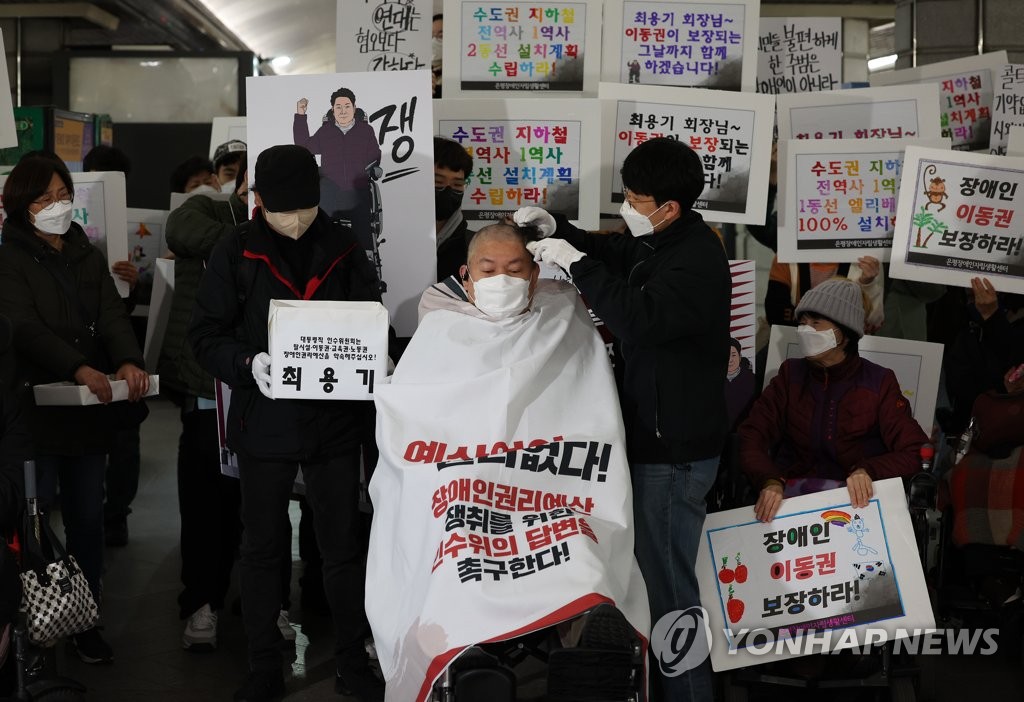 A wheelchair-bound protester has his head shaved in a rally by Solidarity Against Disability Discrimination (SADD) on March 30, 2022, at Gyeongbokgung subway station in central Seoul. (Yonhap)