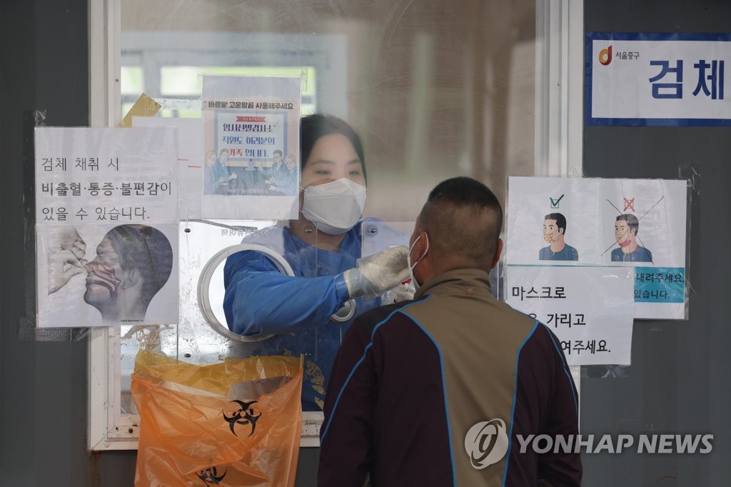 A medical works conducts a COVID-19 test on a person at a temporary testing booth near Seoul Station on April 13, 2022. (Yonhap) 