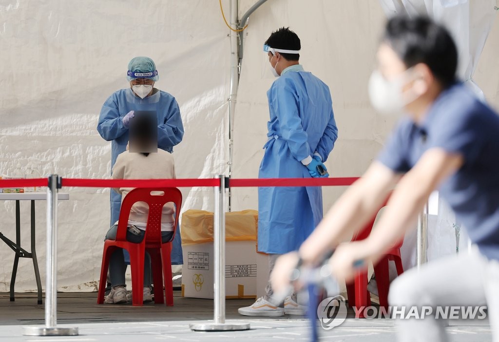 Une citoyenne passe un test de réaction en chaîne par polymérase (PCR) du nouveau coronavirus (Covid-19) au centre installé à la place de Cheonggye à Séoul, le mardi 26 avril 2022. Les autorités sanitaires ont rapporté le même jour 80.361 nouveaux cas confirmés et 82 morts. 