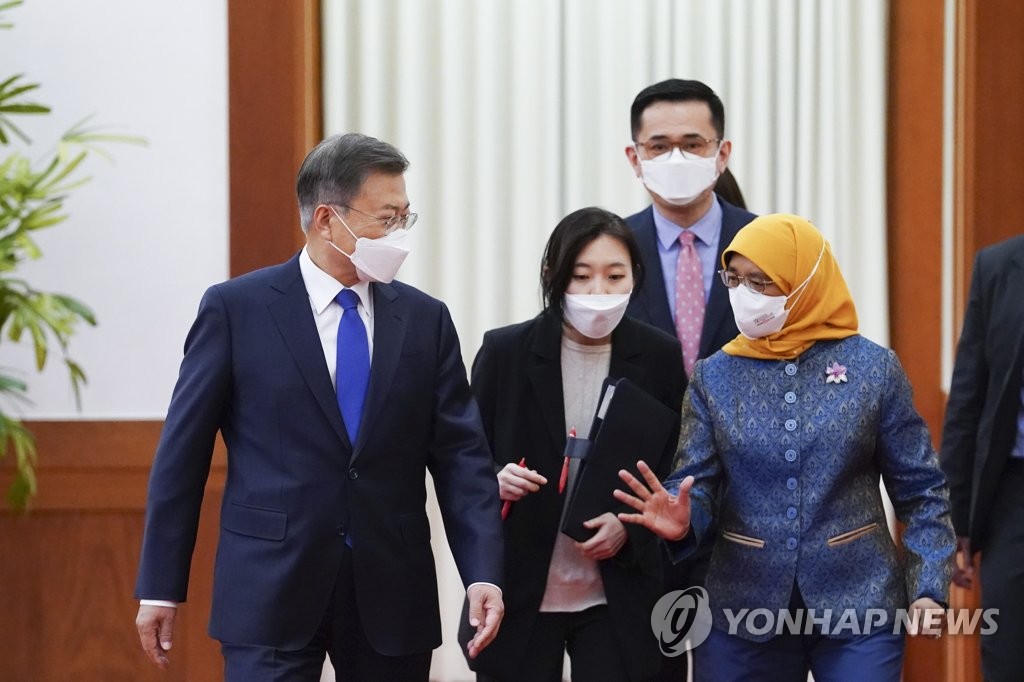 President Moon Jae-in (L) and Singaporean President Halimah Yacob (R) walk at the presidential office in Seoul on May 9, 2022, in this photo released by Cheong Wa Dae. Wang visited Seoul to attend the inaugural ceremony of President-elect Yoon Suk-yeol to be held the following day. (PHOTO NOT FOR SALE) (Yonhap)