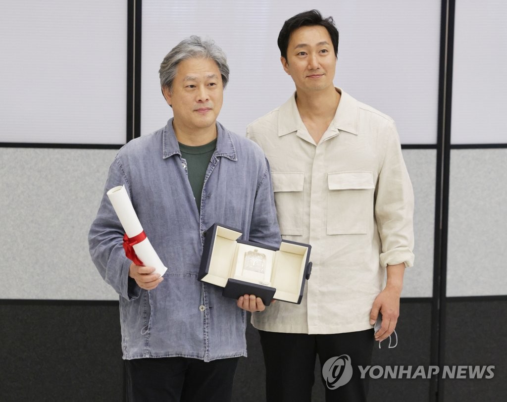 Director Park Chan-wook (L) poses for a photo with his Best Director trophy, which he won at the 75th Cannes Film Festival for the film "Decision to Leave," with actor Park Hae-il upon arrival at Incheon International Airport in Incheon, west of Seoul, on May 30, 2022. (Yonhap)