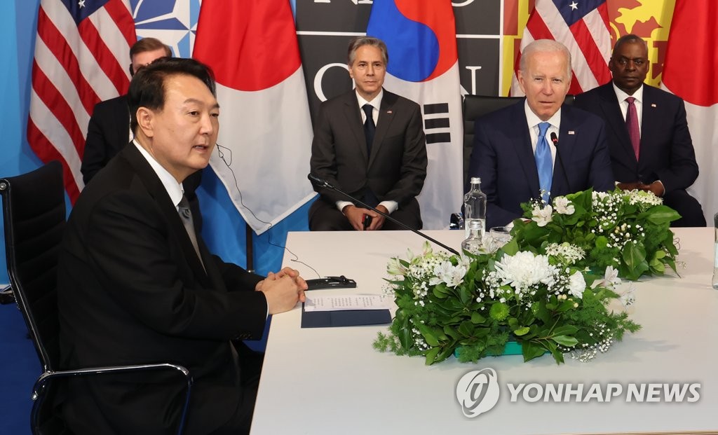 South Korean President Yoon Suk-yeol (L) talks with U.S. President Joe Biden (R, at table) and Japanese Prime Minister Fumio Kishida (not pictured) during a trilateral summit at the IFEMA Convention Center in Madrid on June 29, 2022. (Yonhap)