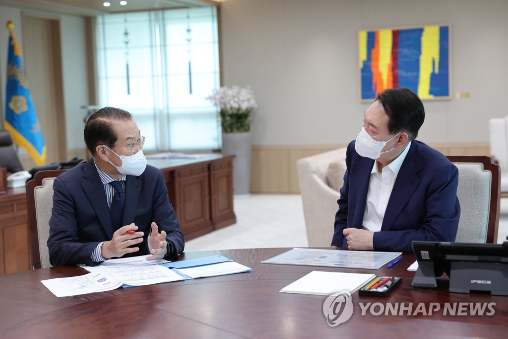 La foto de archivo, proporcionada, el 22 de julio de 2022, por la oficina presidencial surcoreana, muestra al presidente, Yoon Suk Yeol (dcha.), recibiendo un informe sobre las tareas políticas del Ministerio de Unificación por parte de su ministro, Kwon Young-se. (Prohibida su reventa y archivo)