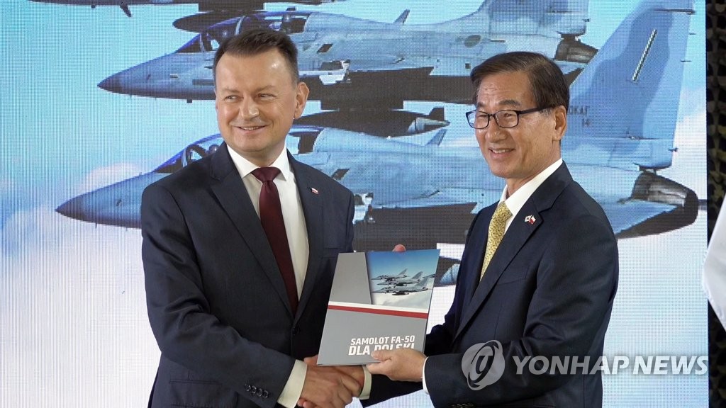 Kang Goo-young (R), CEO of Korea Aerospace Industries, and Polish Defense Minister Mariusz Błaszczak shake hands after signing an agreement to implement an earlier deal for KAI's provision of 48 FA-50 fighter jets to Poland, during a ceremony in Minsk Mazowiecki, Poland, on Sept. 16, 2022, in this photo provided by the Defense Acquisition Program Administration. (PHOTO NOT FOR SALE) (Yonhap)