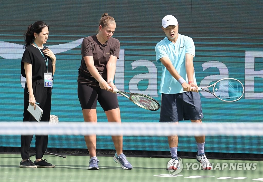 Latvian tennis player Jelena Ostapenko (C) works with an amateur player during her clinic at Olympic Park Tennis Center in Seoul on Sept. 18, 2022, on the eve of the WTA Hana Bank Korea Open. (Yonhap)