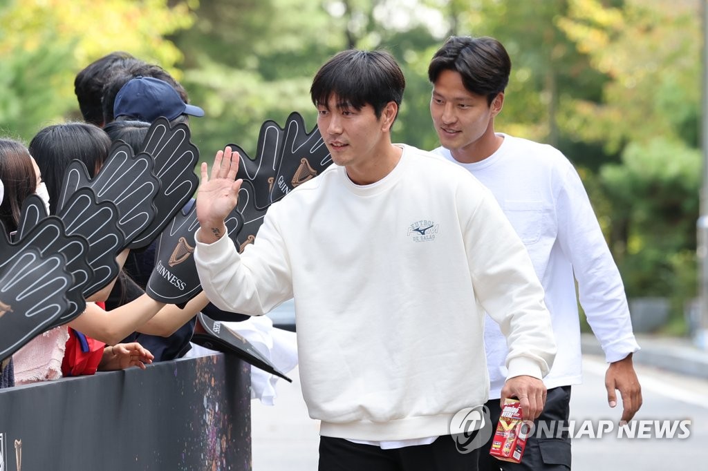 South Korean football players Kim Young-gwon (front) and Kwon Kyung-won high-five fans outside the National Football Center in Paju, Gyeonggi Province, before reporting to the national team's training camp on Sept. 19, 2022, ahead of friendly matches against Costa Rica and Cameroon. (Yonhap)