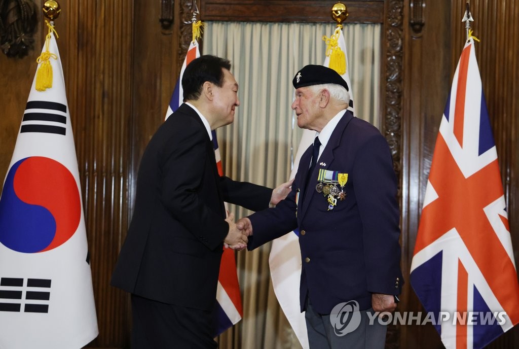 President Yoon Suk-yeol (L) shakes hands with Victor Swift, a British Korean War veteran, after presenting him with the Civil Merit Medal at a hotel in London on Sept. 19, 2022. (Yonhap)