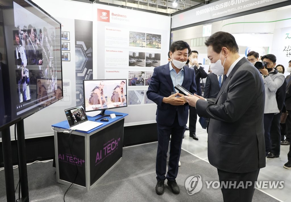 El presidente, Yoon Suk-yeol (dcha.), sostiene una foto de su infancia que fue transformada de blanco y negro a color usando una tecnología de IA, el 28 de septiembre de 2022, en la exhibición "AI Tech+ 2022", en el Centro de Convenciones Kimdaejung, en Gwangju, a 268 kilómetros al sur de Seúl.
