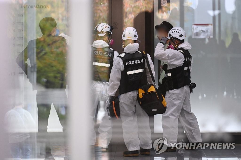La foto, tomada el 16 de octubre de 2022, muestra a unos investigadores de la policía y bomberos entrando en el edificio de SK C&C, que alberga los centros de datos de Kakao y Naver, situado en Pangyo, al sur de Seúl, para efectuar la primera investigación de la causa del incendio ocurrido, el 15 de octubre, en el recinto. (Yonhap)