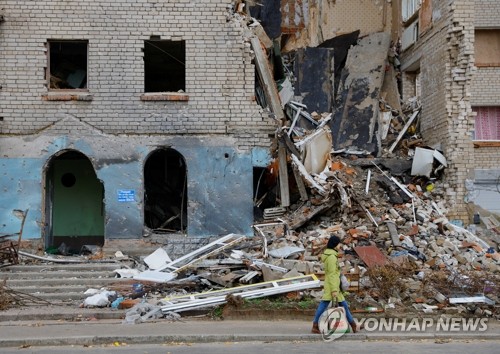 파괴된 건물 지나치는 우크라이나 시민
