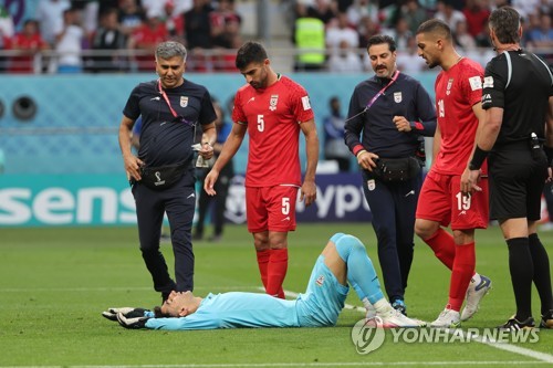 Iran goalkeeper Alireza Beiranvand (C) stays on the pitch after suffering a head injury during Iran's Group B match against England at the FIFA World Cup at Khalifa International Stadium in Al Rayyan, just west of Doha, on Nov. 21, 2022. (Yonhap)