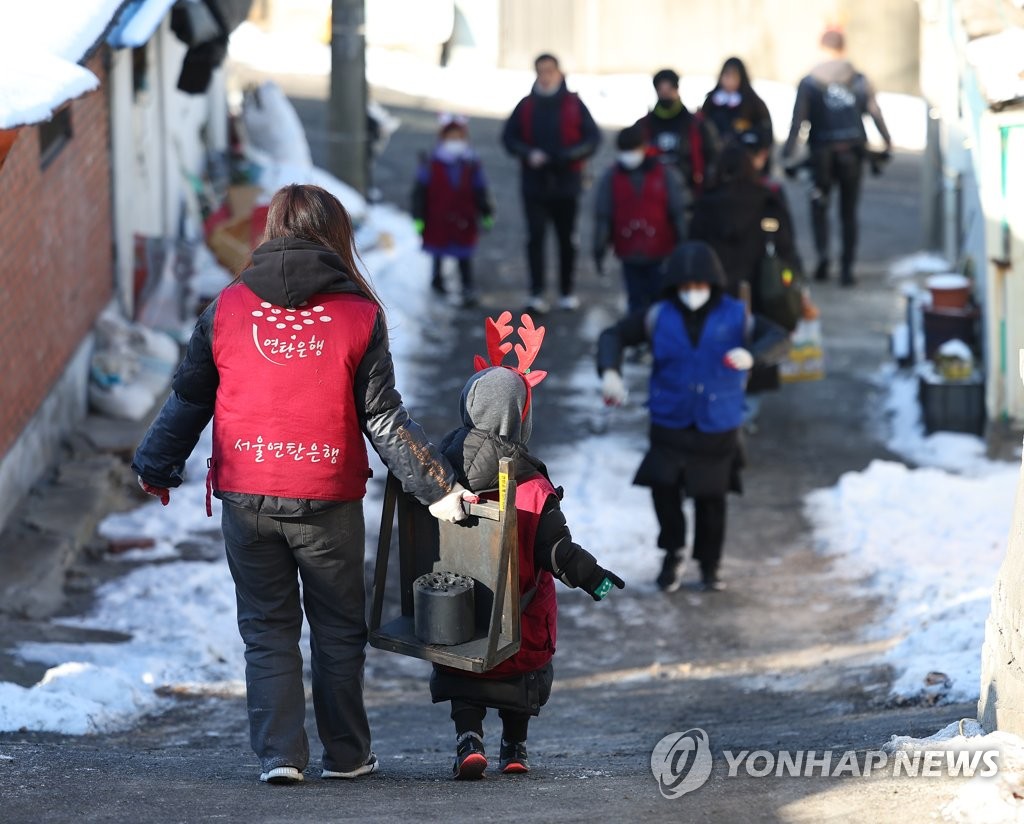엄마 도움 받으며 연탄 옮기는 어린이