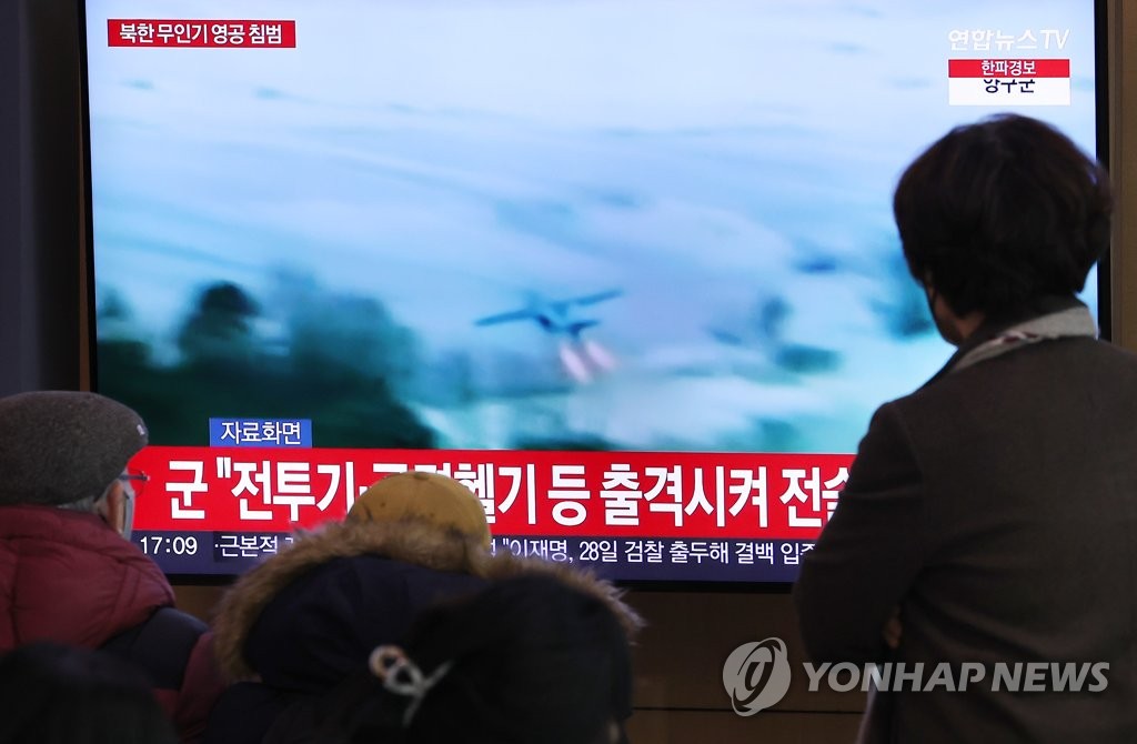 ソウル駅のテレビで北朝鮮の無人機に関するニュースを見る人たち＝２６日、ソウル（聯合ニュース）