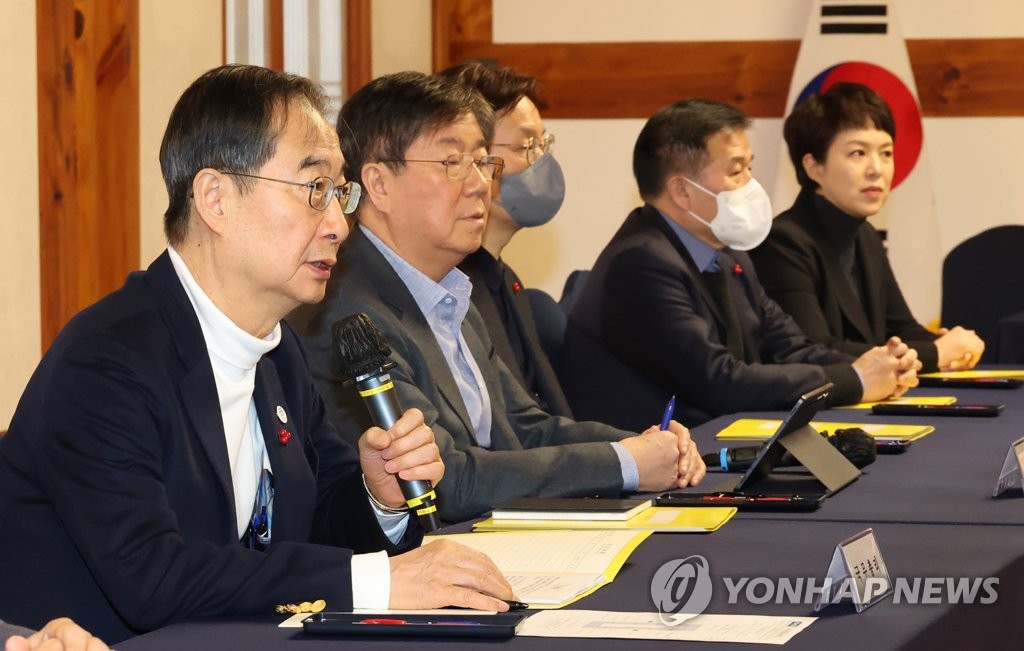 El primer ministro Han Duck-soo (izquierda) habla durante una reunión con miembros de alto rango de la oficina presidencial y el gobernante Partido del Poder Popular en la Asamblea Nacional el 8 de enero de 2023. (Yonhap)