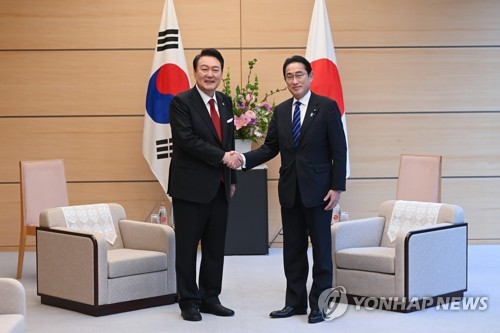 Le président sud-coréen Yoon Suk Yeol (à g.) et le Premier ministre japonais Fumio Kishida échangent une poignée de main avant leur sommet élargi à la résidence de ce dernier à Tokyo, le jeudi 16 mars 2023.