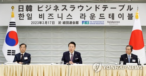 El presidente surcoreano, Yoon Suk Yeol (centro), pronuncia un discurso en una mesa redonda con líderes empresariales de Corea del Sur y Japón, el 17 de marzo de 2023, en el edificio de la Federación Empresarial de Japón (Keidanren), en Tokio, flanqueado por Kim Byong-joon (izda.), jefe interino de la FKI, y Masakazu Tokura, jefe de Keidanren.
