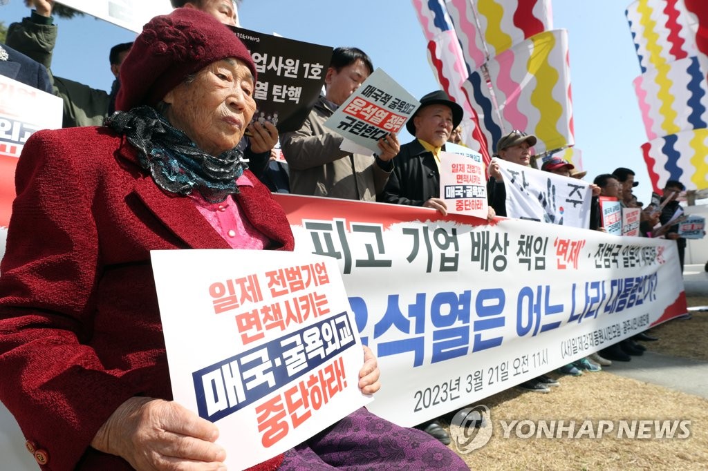 韓日首脳会談の結果を非難する徴用被害者の梁錦徳さん（手前）と支援団体。旧日本軍の慰安婦被害者を象徴する「平和の少女像」前で記者会見を開いた＝２１日、光州（聯合ニュース）