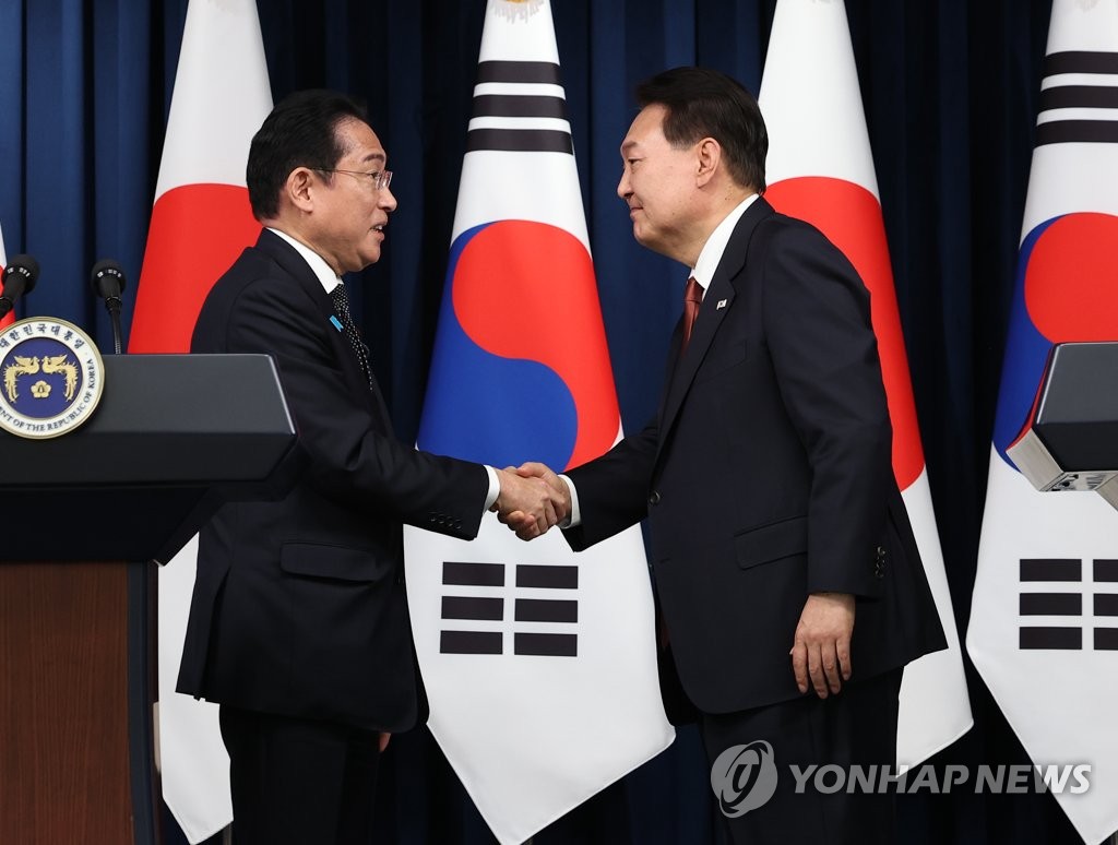 South Korean President Yoon Suk Yeol (R) and Japanese Prime Minister Fumio Kishida shake hands after holding a joint press conference at the presidential office in Seoul on May 7, 2023. During their talks, Yoon and Kishida agreed to allow a group of South Korean experts to visit Japan to inspect the planned release of radioactive water from the crippled Fukushima nuclear power plant. (Yonhap)
