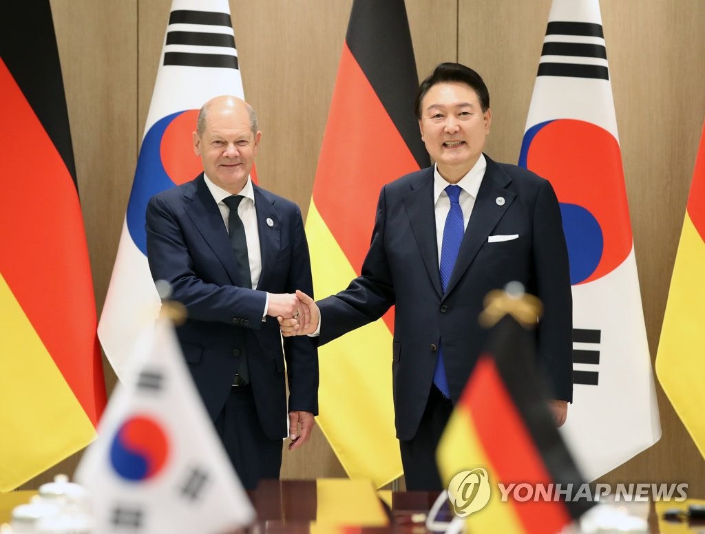 South Korean President Yoon Suk Yeol (R) and German Chancellor Olaf Scholz shake hands during their summit at the presidential office in Seoul on May 21, 2023. (Yonhap)