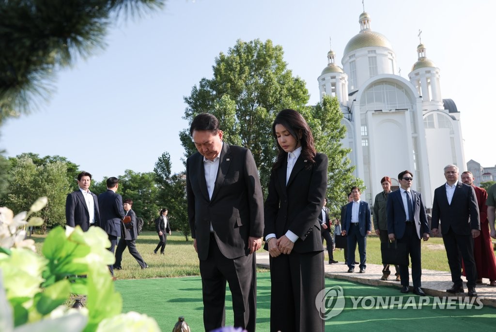 South Korean President Yoon Suk Yeol (L) and first lady Kim Keon Hee bow their heads in tribute at the grave of a victim of mass killings in Bucha, Ukraine, on July 15, 2023, in this photo provided by the presidential office. (PHOTO NOT FOR SALE) (Yonhap)