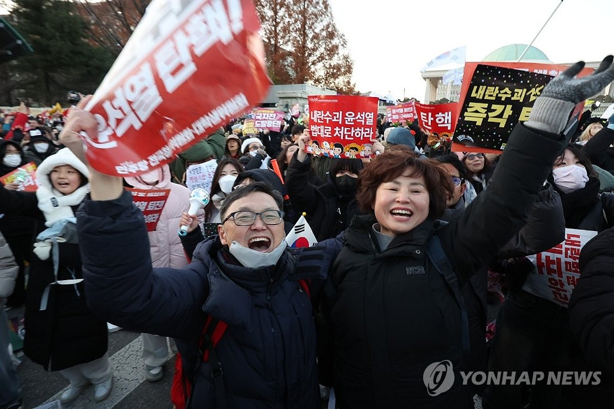 Los manifestantes aplauden cerca de la Asamblea Nacional en Seúl el 14 de diciembre de 2024, tras la aprobación de una moción de juicio político contra el presidente Yoon Suk Yeol. La moción fue aprobada con una votación de 204-85, incluidas tres abstenciones y ocho votos nulos. (Yonhap)